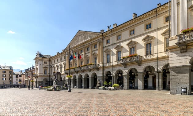 Det store torv Piazza Emile Chanoux i Aosta omgivet af klassiske bygninger og Alperne i baggrunden