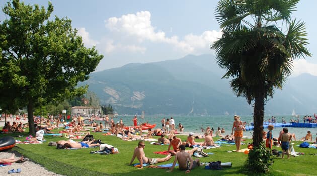 Pini-stranden i Riva del Garda Pini-stranden i Riva del Garda med bjerge og badegæster