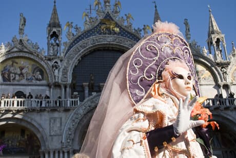 Deltagere i farverige, historiske kostumer og detaljerede masker under karnevallet i Venedig